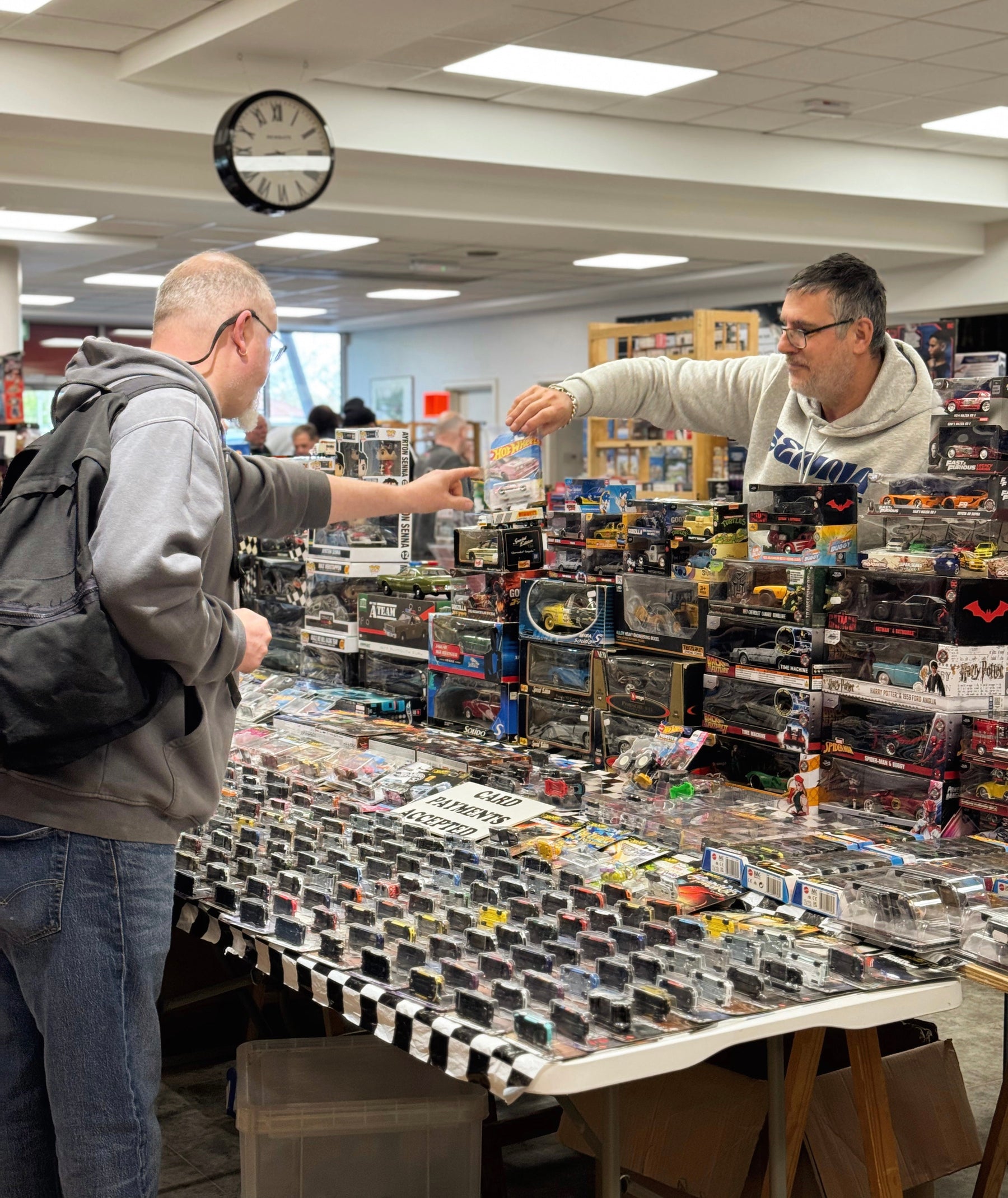 Dealer showing a visitor a packaged model car at Kempton Park Toy Fair